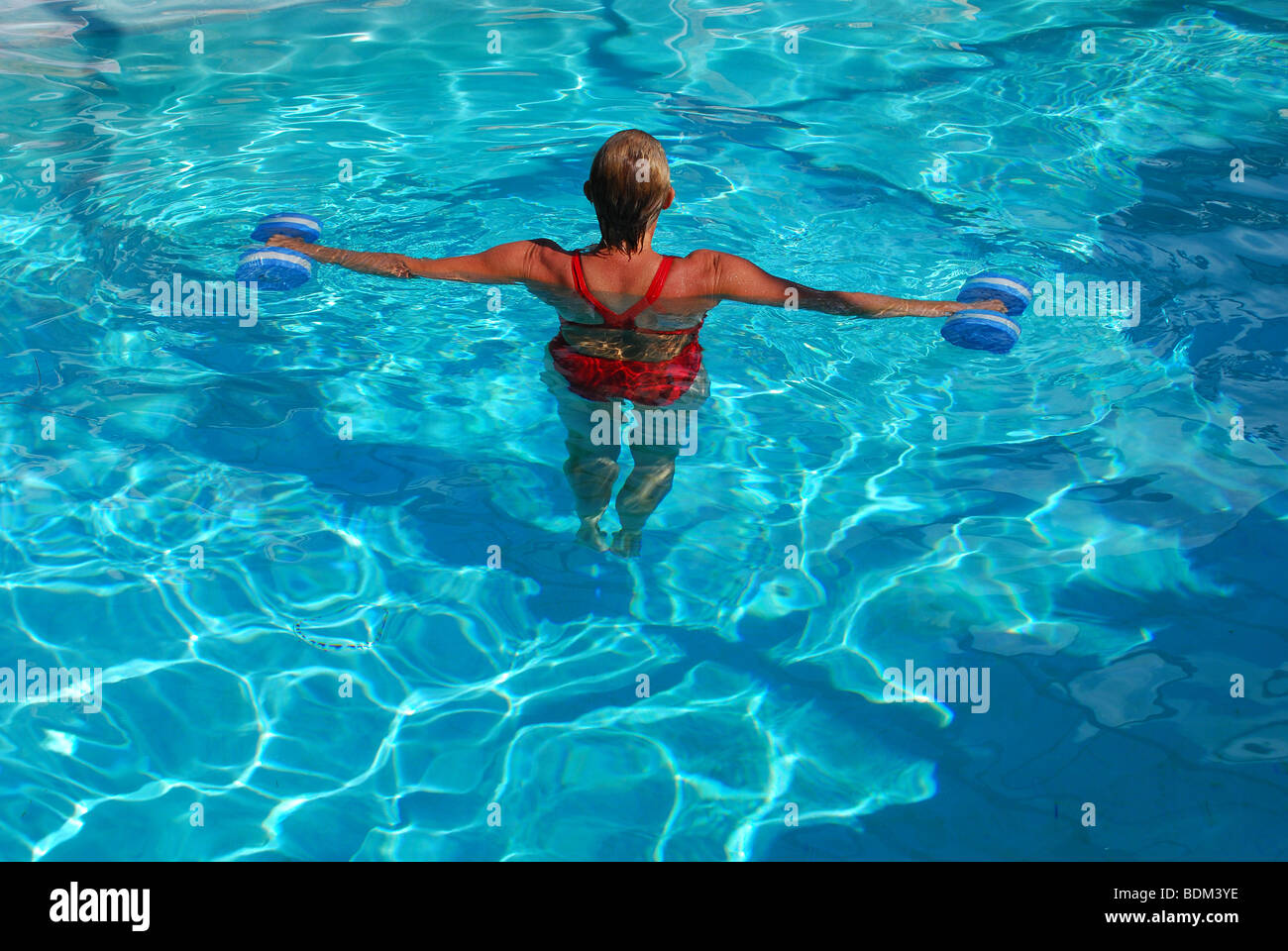 Healthy adult woman exercises with weights in swimming pool Stock Photo