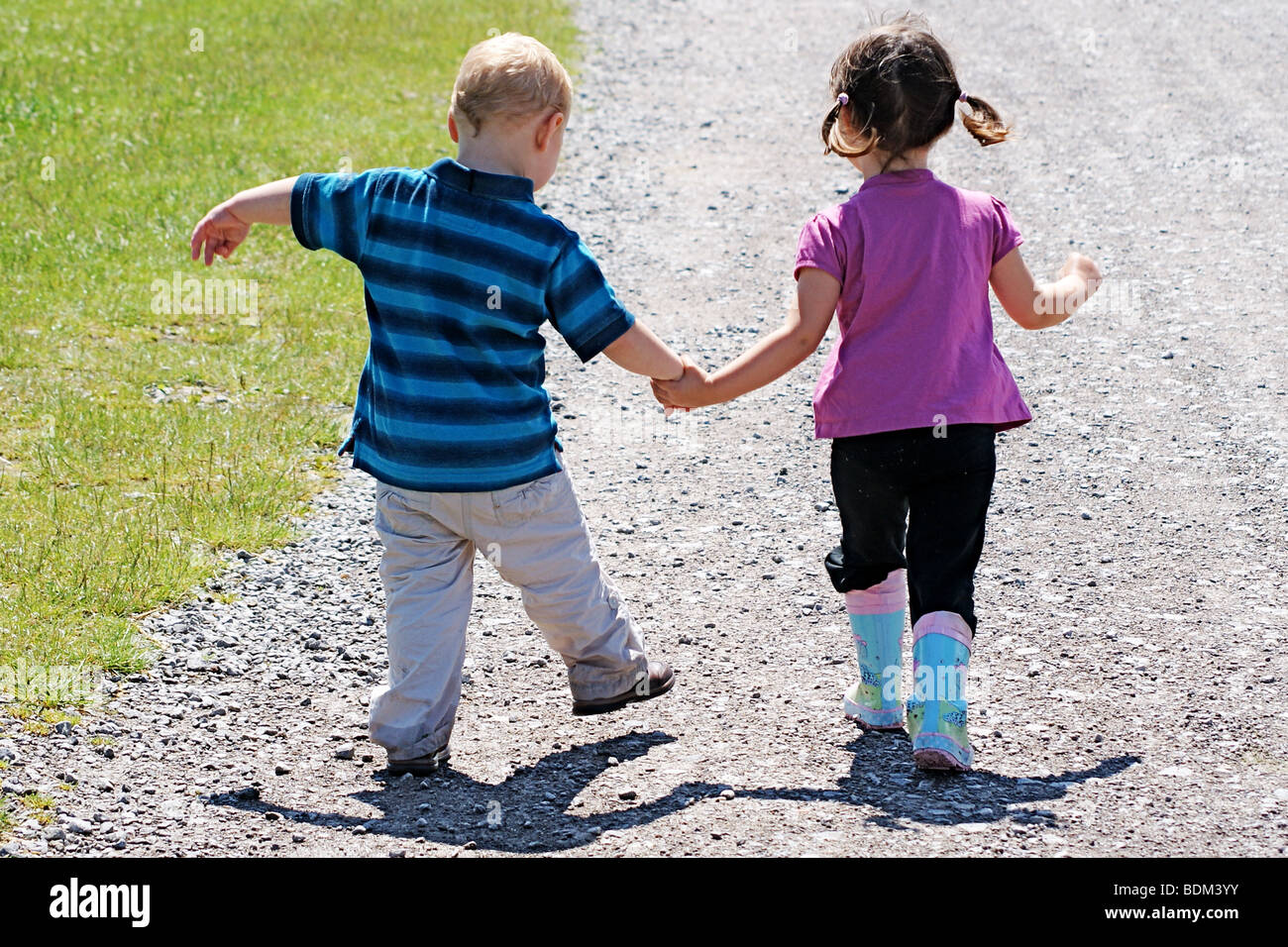 Young Boy And Girl Toddlers Friends Walking Together Holding Hands