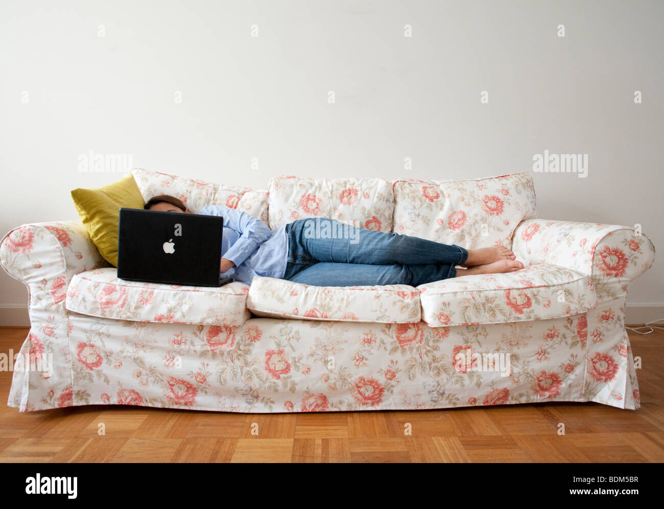Young woman lying on sofa at home working with a laptop computer Stock ...