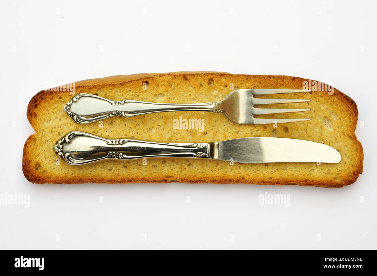 A pair of knife and folk on a slice of dried grilled bread. Stock Photo