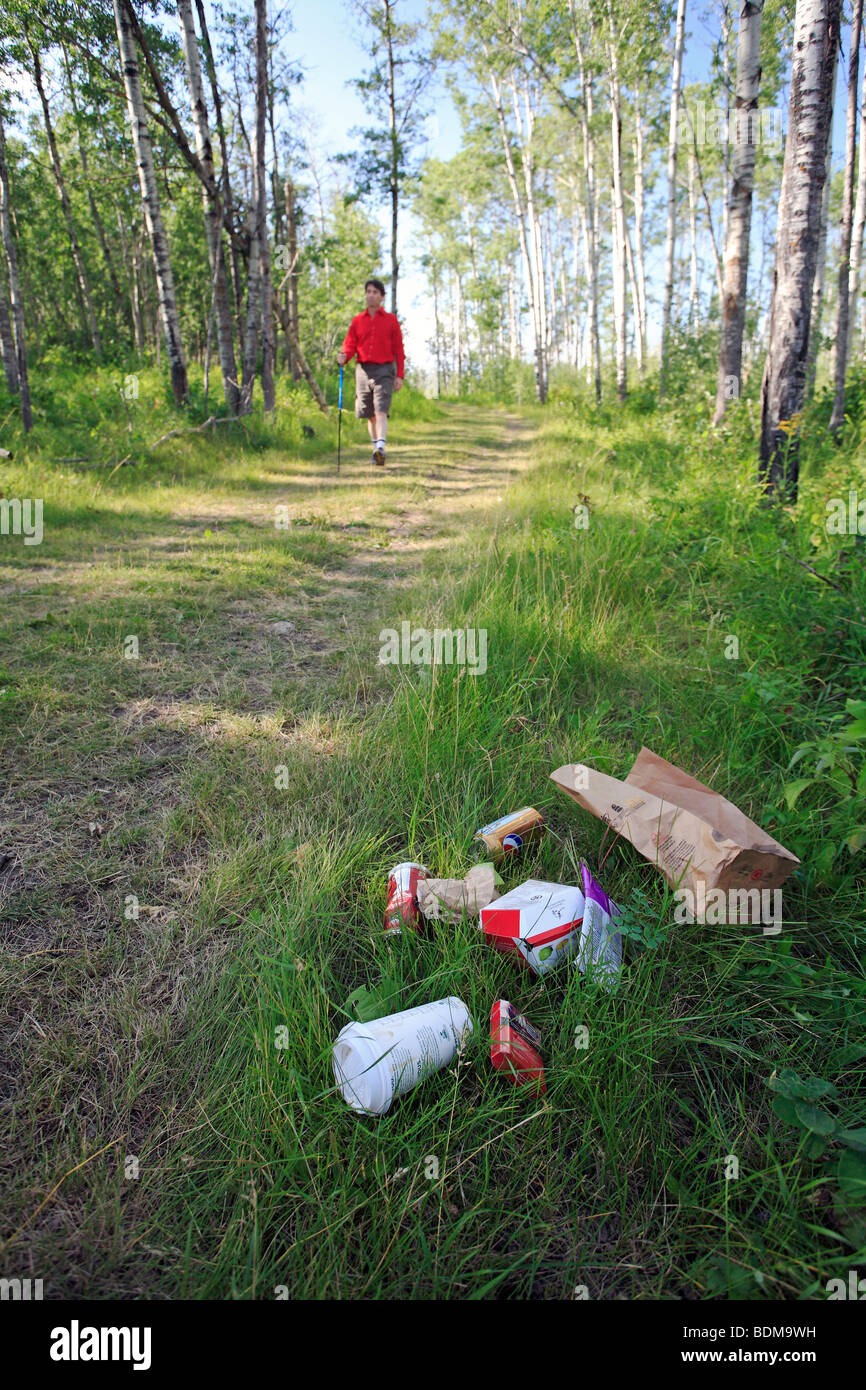 Middle age male hiking on forest trail with garbage on the ground. Stock Photo