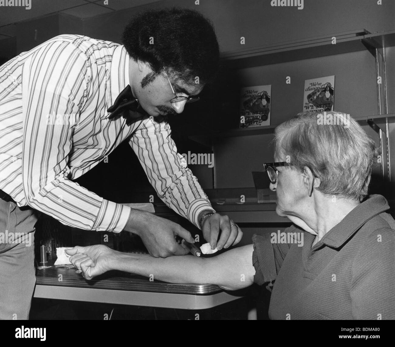 1976 photograph.  A health professional drawing blood from an elderly man for testing during the swine flu vaccination camp Stock Photo