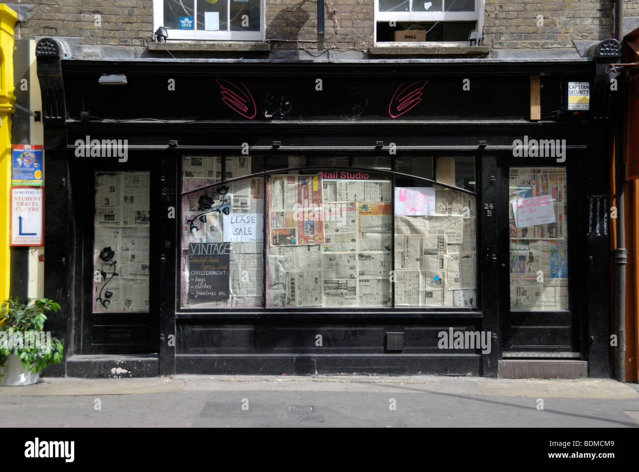 Vacant UK shop premisis with windows covered in newspaper Stock Photo