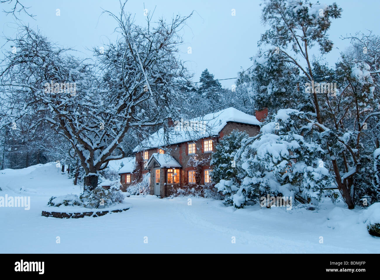 Christmas card image of a cosy cottage in Hampshire, at dusk with all the windows lit Stock Photo