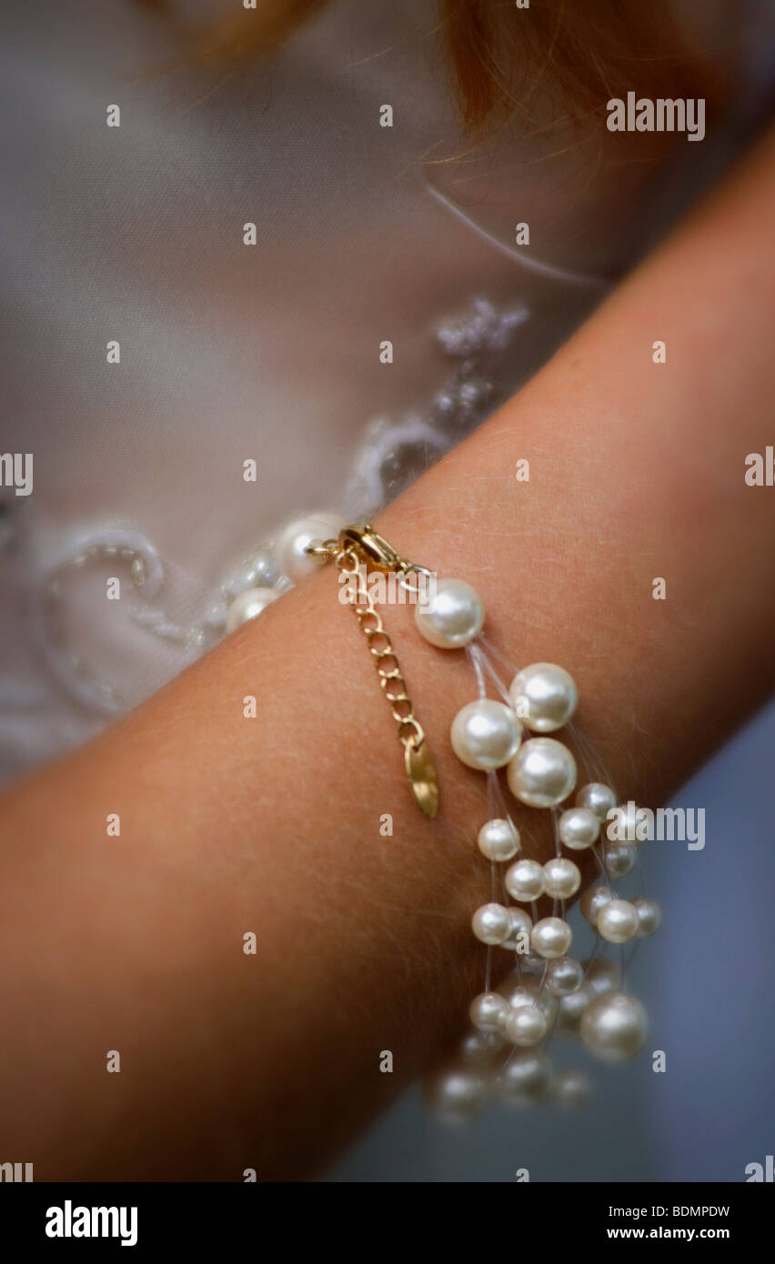 young womans wrist wearing pearl and gold bracelet Stock Photo