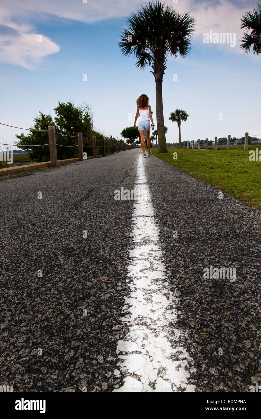 Woman walking along a white line in Mount Pleasant, South Carolina. Stock Photo