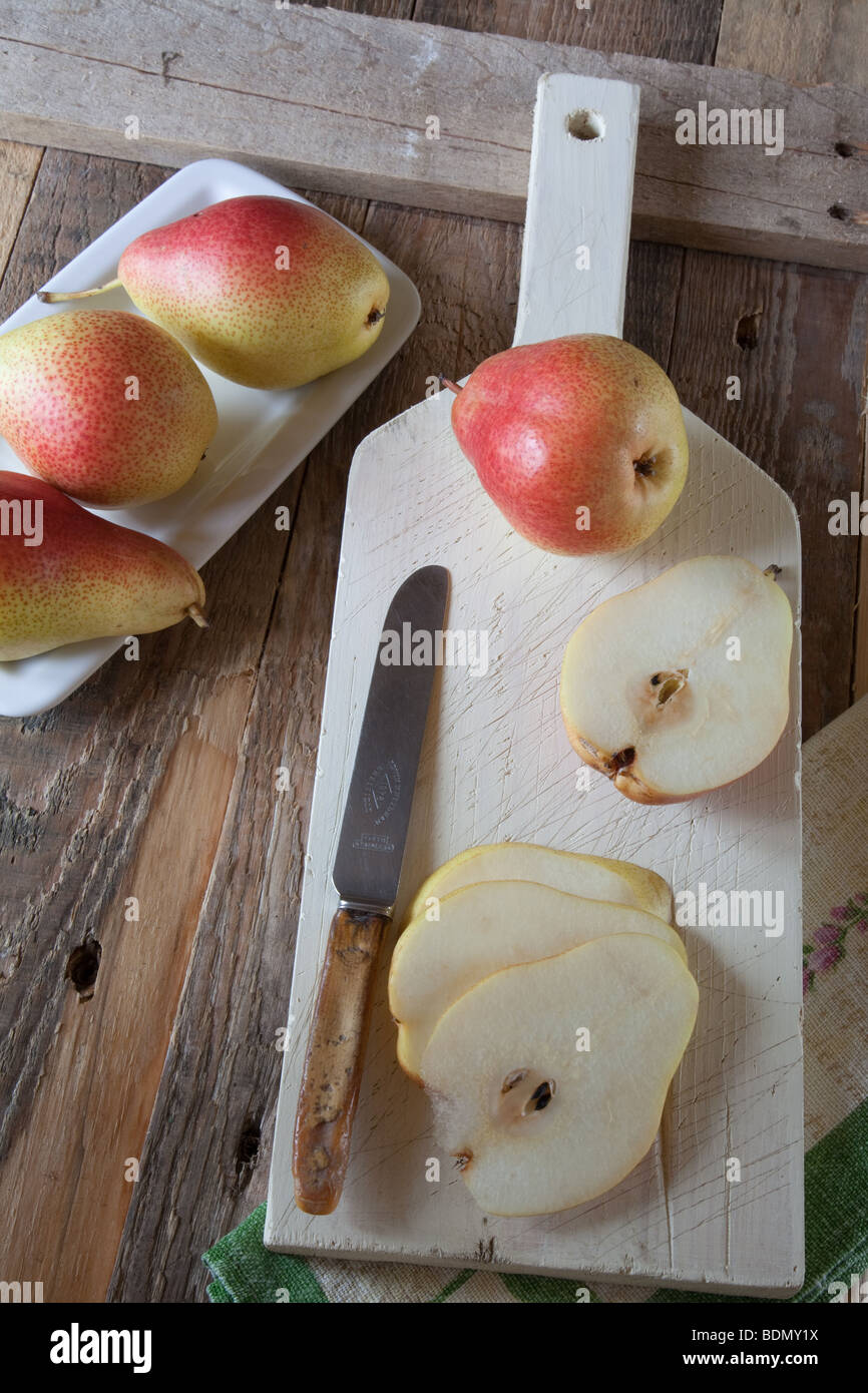 Pears [Forelle]  whole and sliced on a white chopping board with a knife Stock Photo
