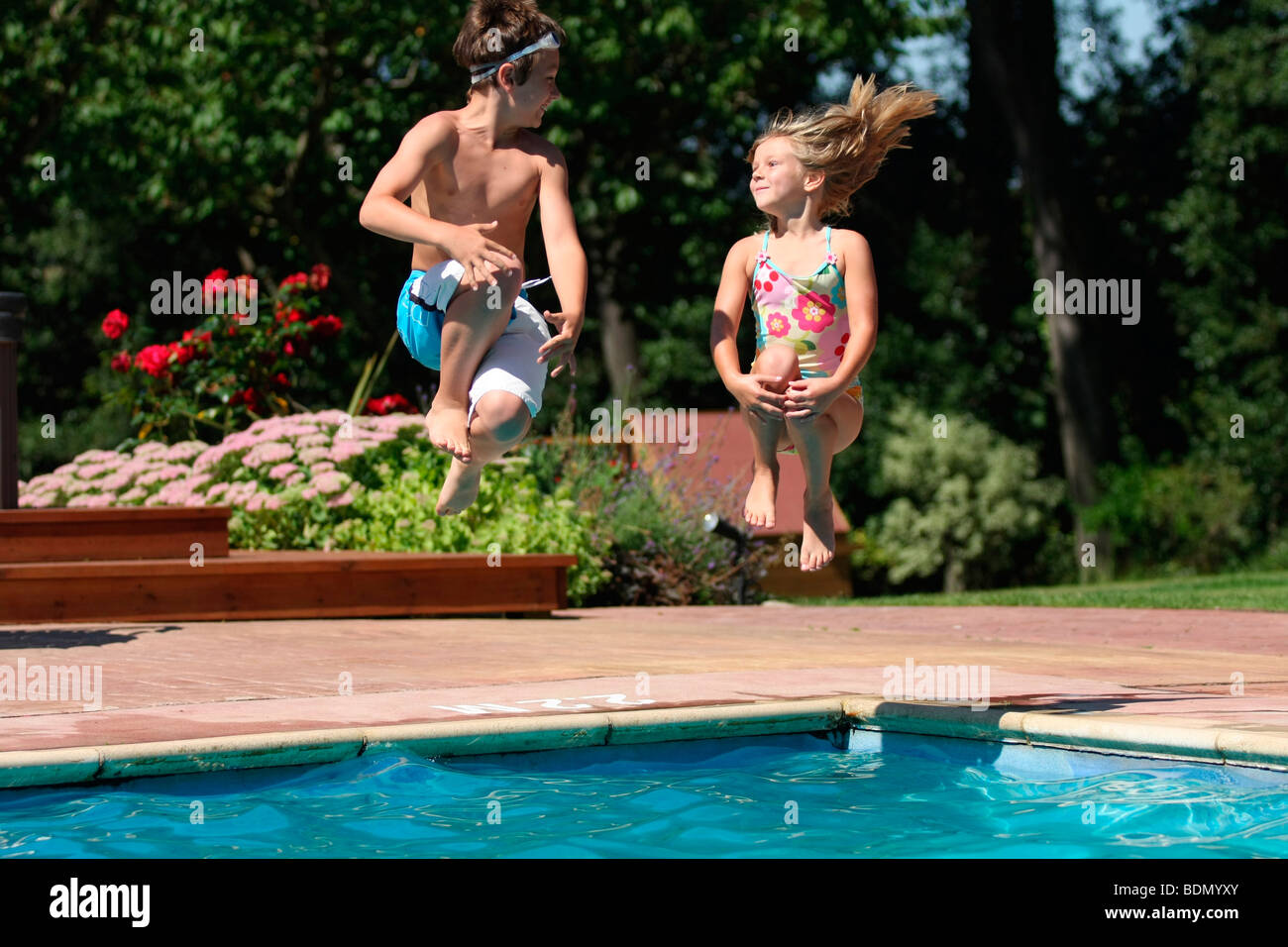 Girl and Boy jumping in swimming pool Stock Photo Alamy