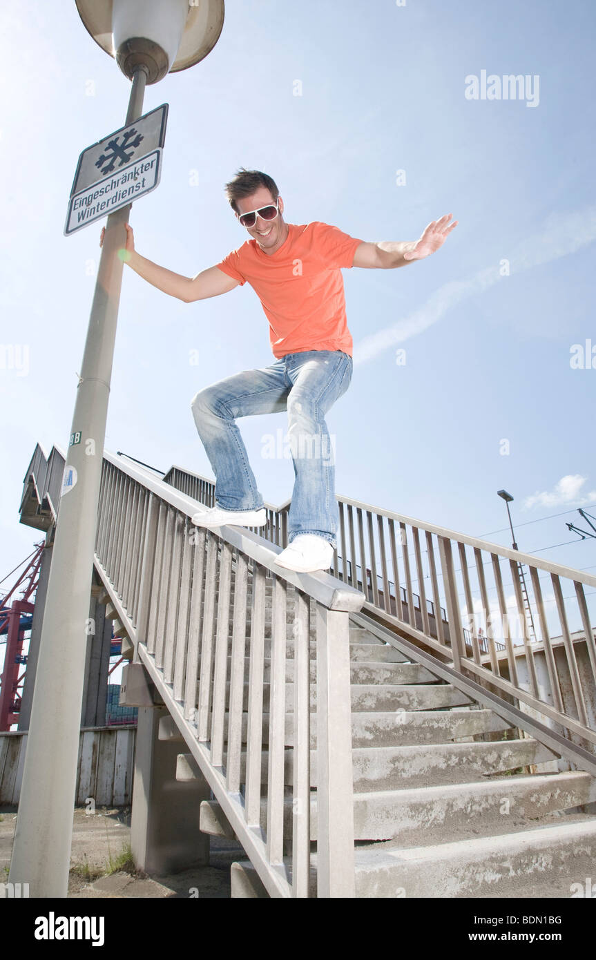 Young man sliding down the railing of a pedestrian bridge Stock Photo