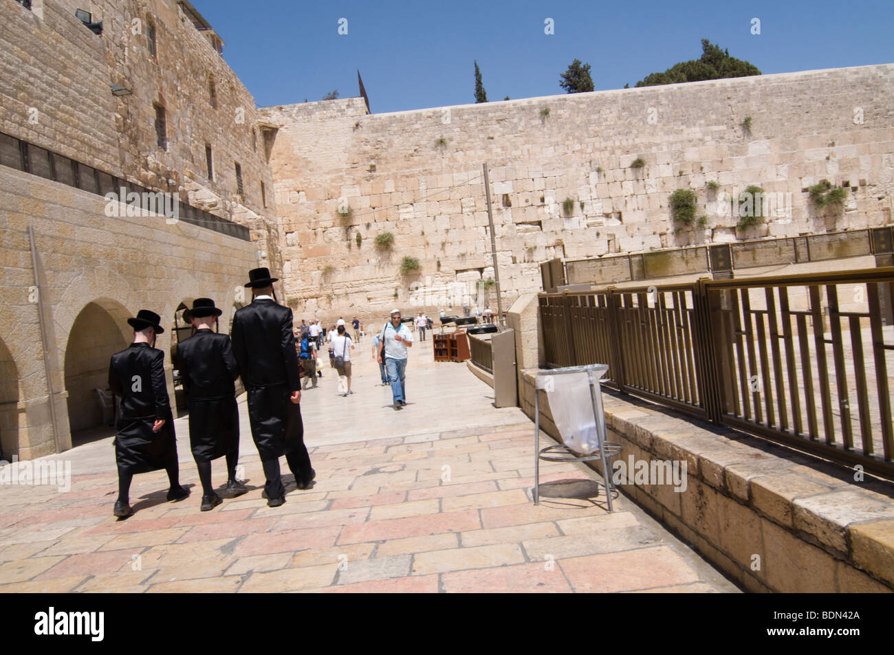 Hasidic Jewish young men wearing bekishe, long satin coats, walk toward the Western Wall for Sabbath prayers. Stock Photo