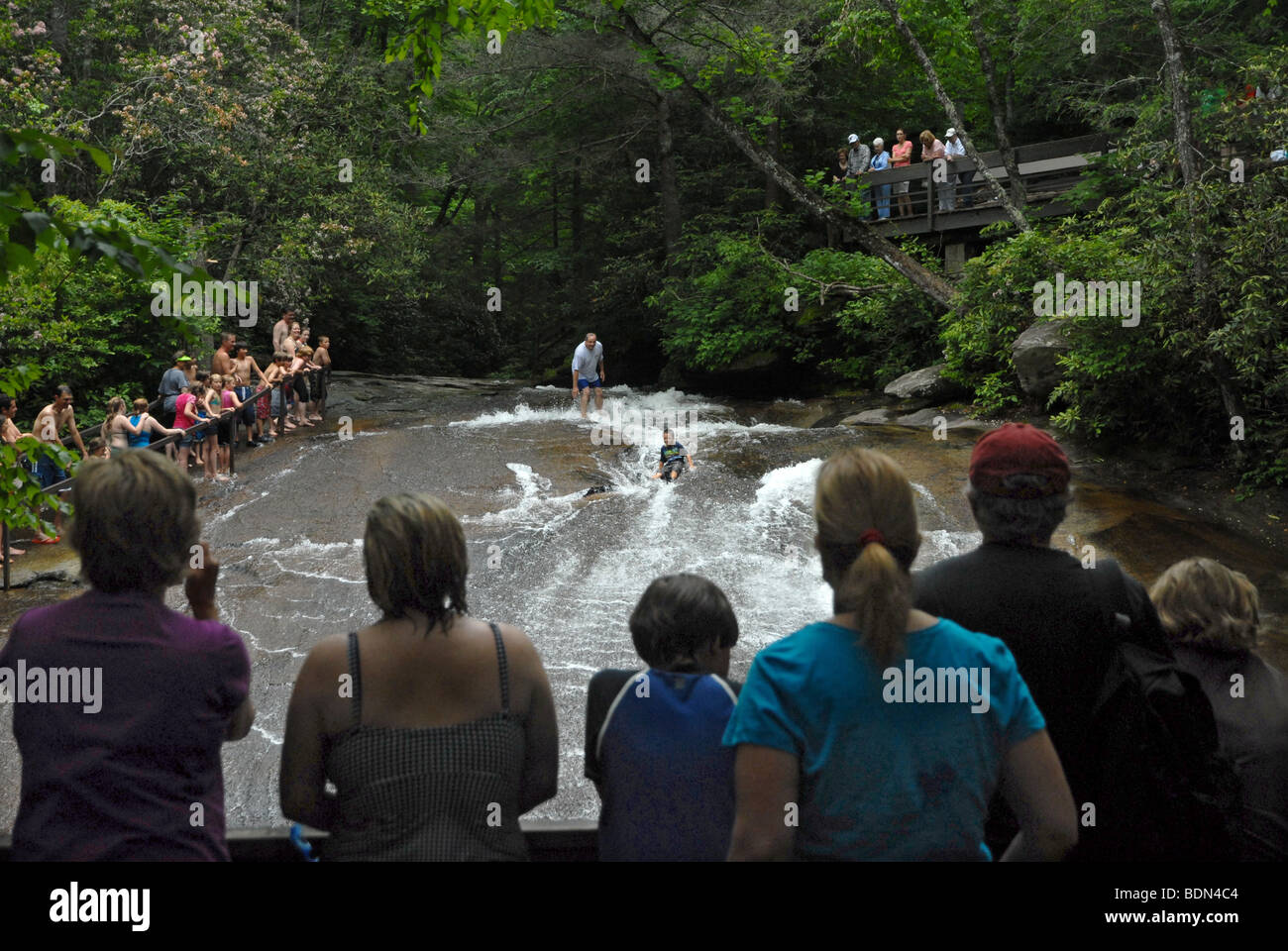 People look at young boy slides down a flat rock water slide in North Carolina. Stock Photo