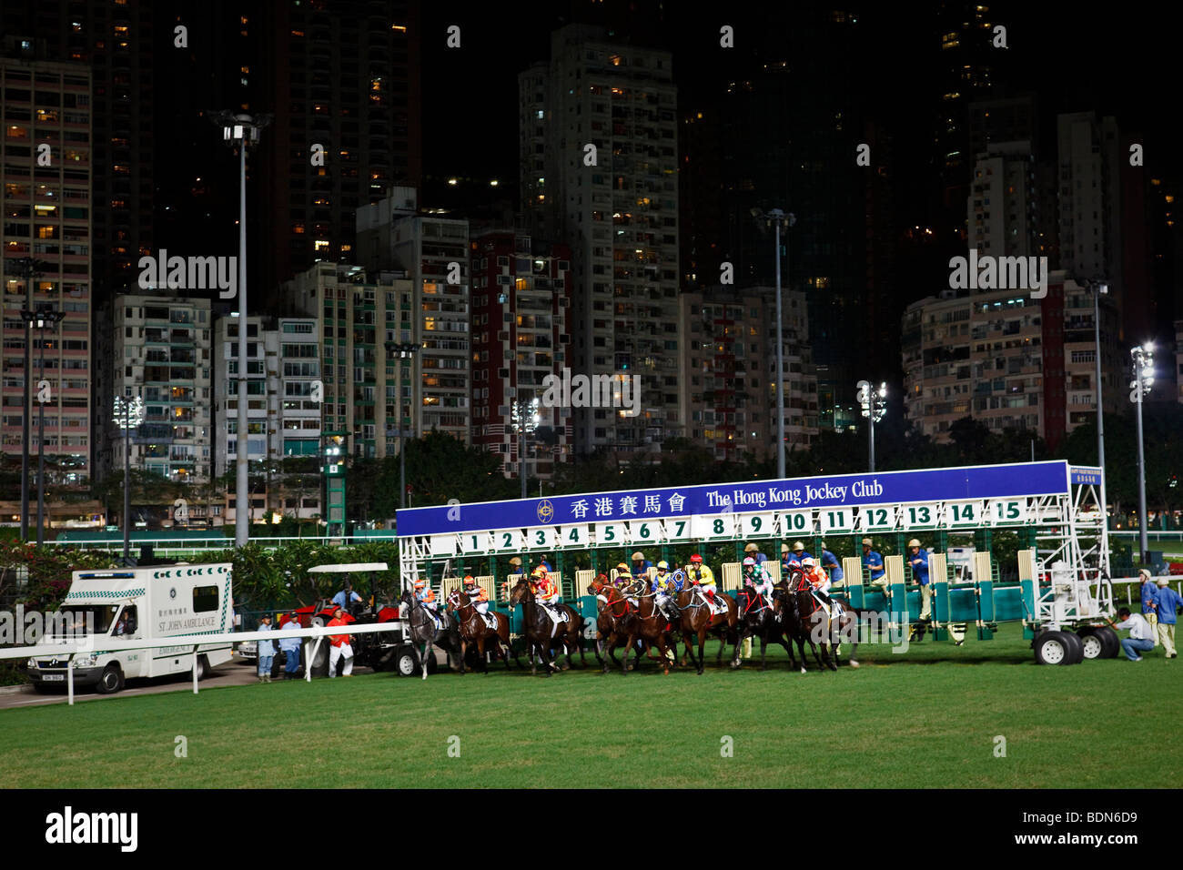 Race horses jump out of the starting gates at a night horse racing event at the Happy Valley race course in Hong Kong. Stock Photo