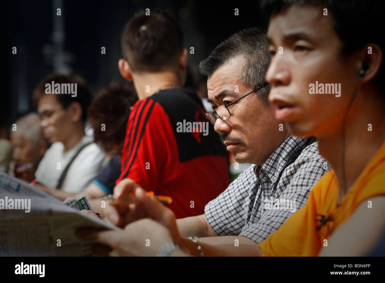 Punters study the race form at a night horse racing event at the Happy Valley race course in Hong Kong. Stock Photo