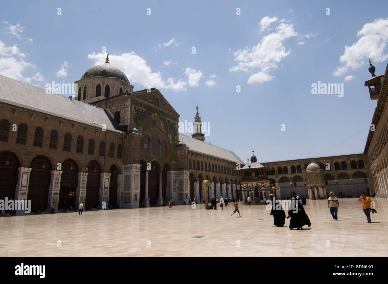 Veiled women in black and casually dressed men walk through the courtyard of the Umayyad Mosque (Grand Mosque of Damascus), carr Stock Photo