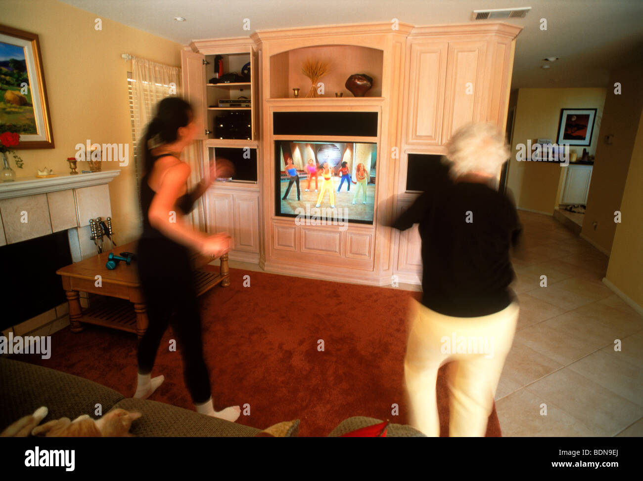 Mother and Grandmother exercising at home to TV video Stock Photo