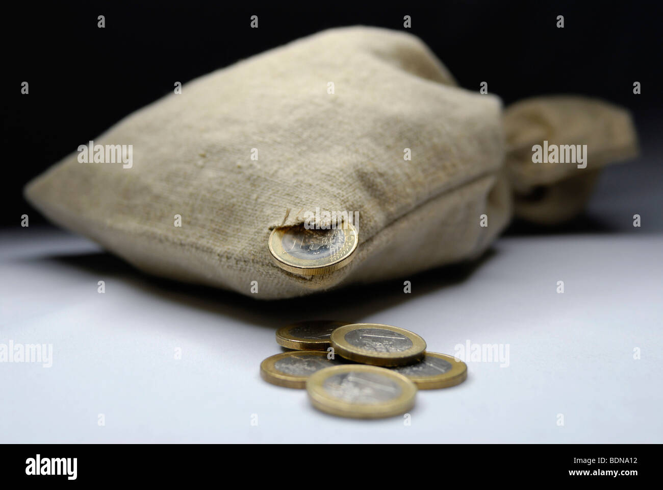 Money bag with hole and euro coins, symbolic image for financial hole, losing money Stock Photo