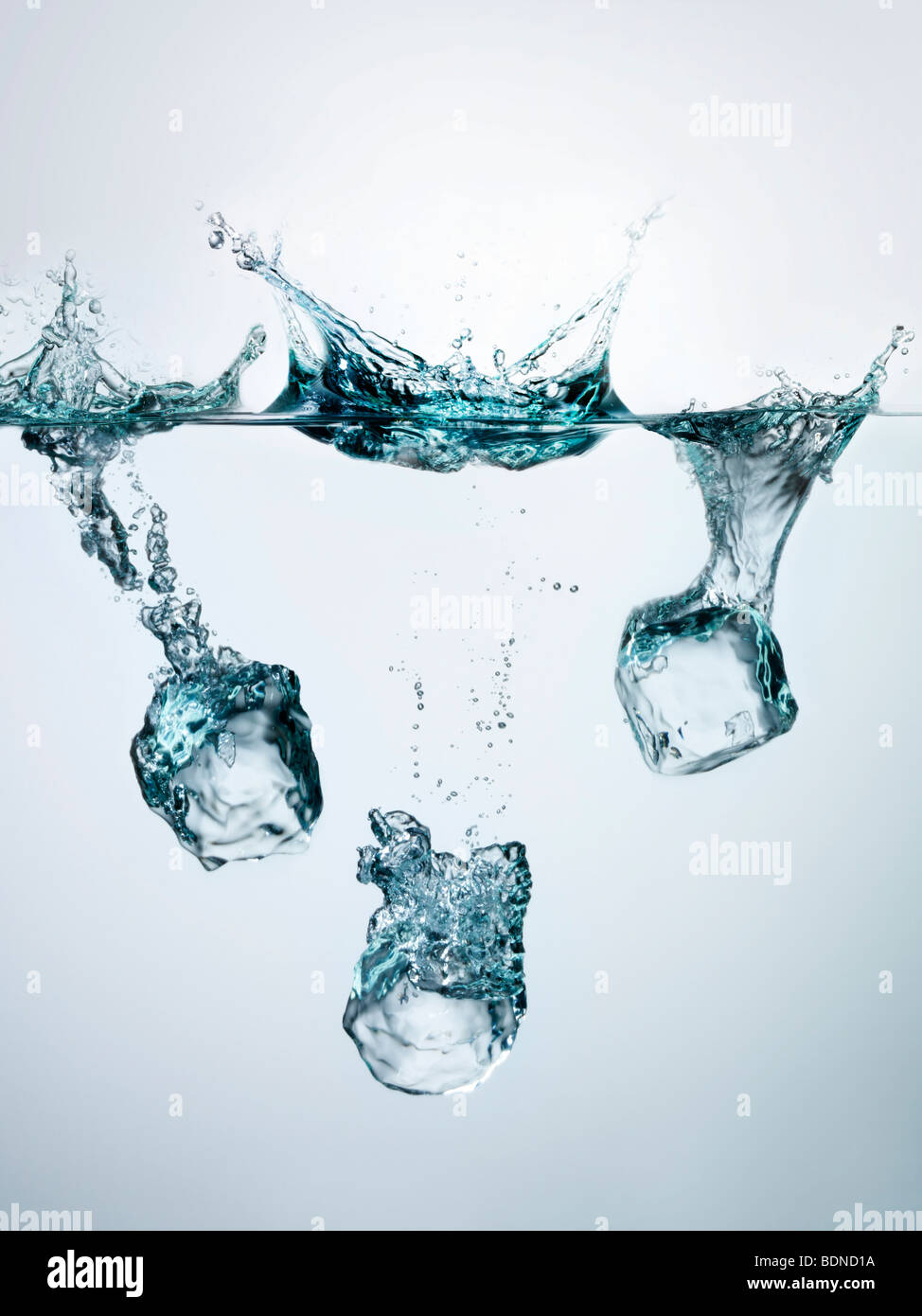 Ice cubes splashing into clear water, surface view Stock Photo