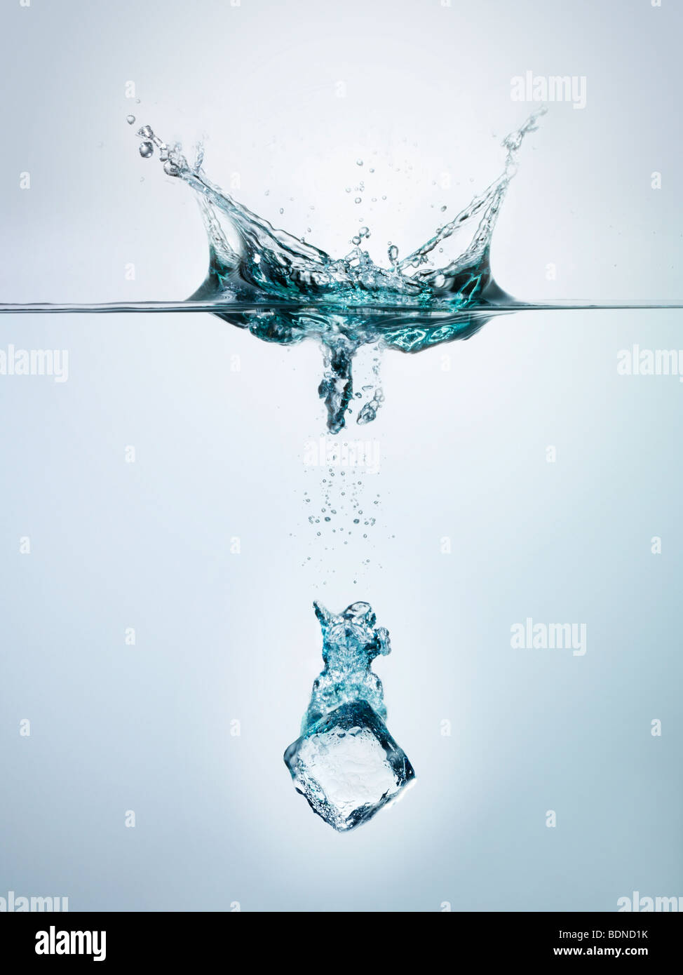 Ice cube splashing into clear water, surface view Stock Photo