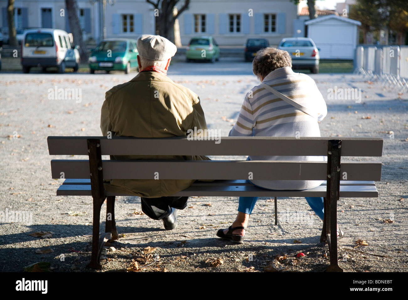 An old couple relaxing one evening on a bench in a square Saint Martin de Re on Ile de Re, France. Stock Photo
