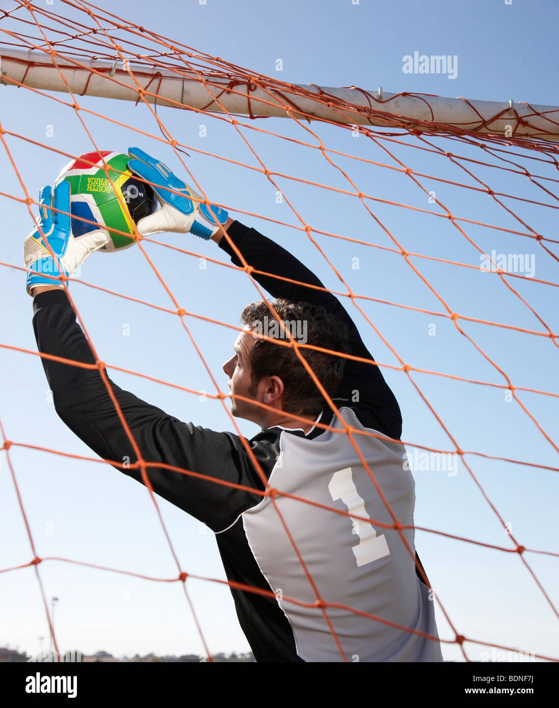 Goalie reaching up to soccer ball in front of nets. Cape Town, Western Cape Province, South
