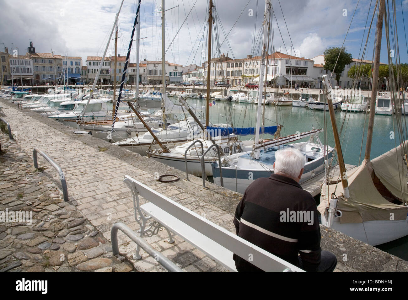 An old man sits in the harbour of Le Flotte on Ile de Re, France. Stock Photo