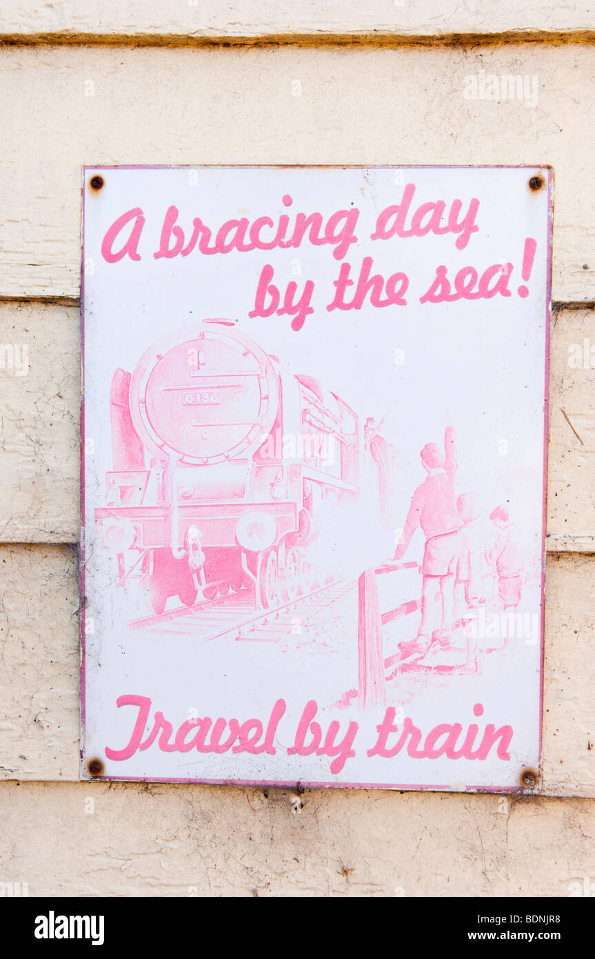 An old weathered sign on a Uk railway station advertising rail travel Stock Photo