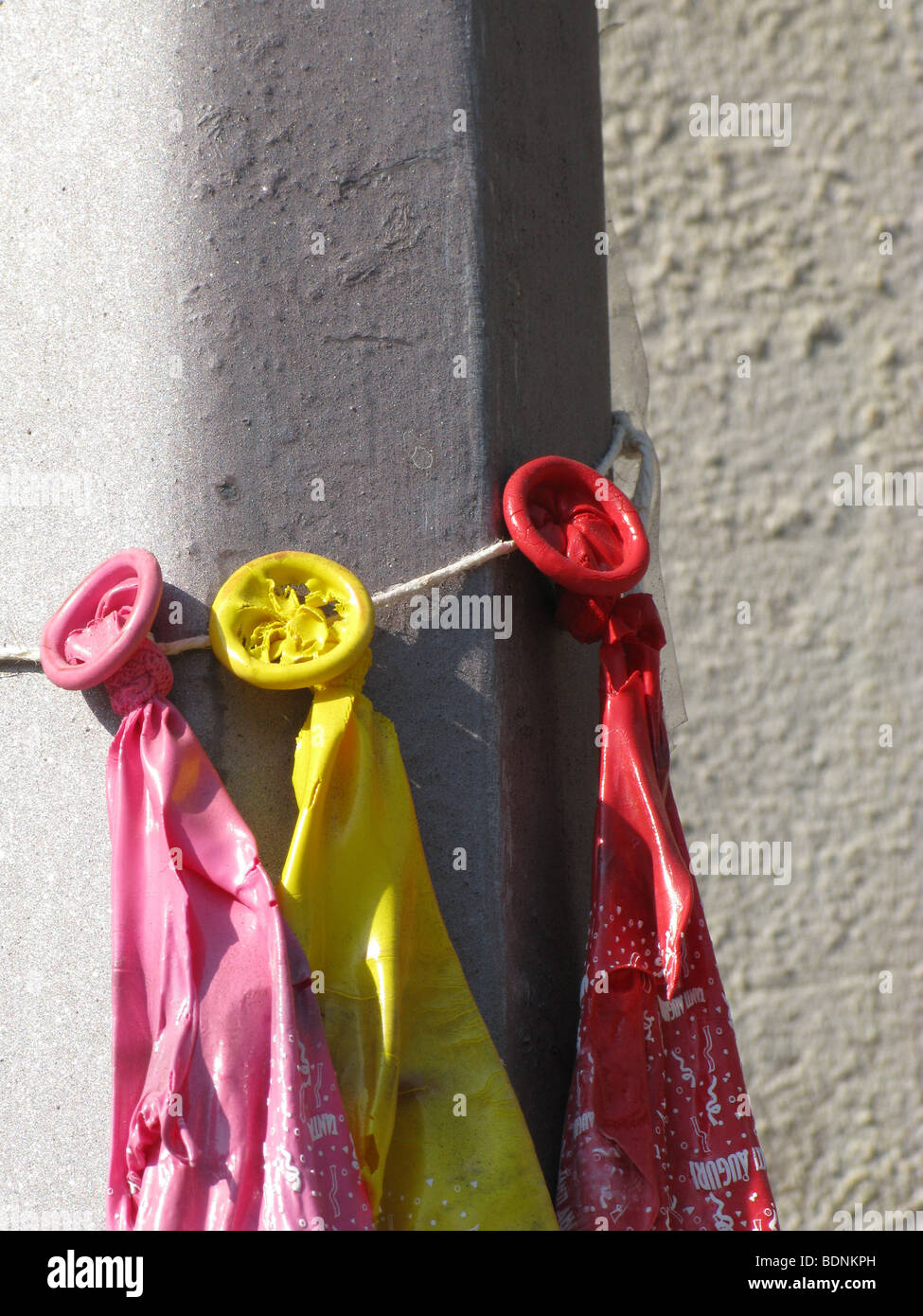 three burst balloons tied to lamp post outdoors in sun Stock Photo Alamy