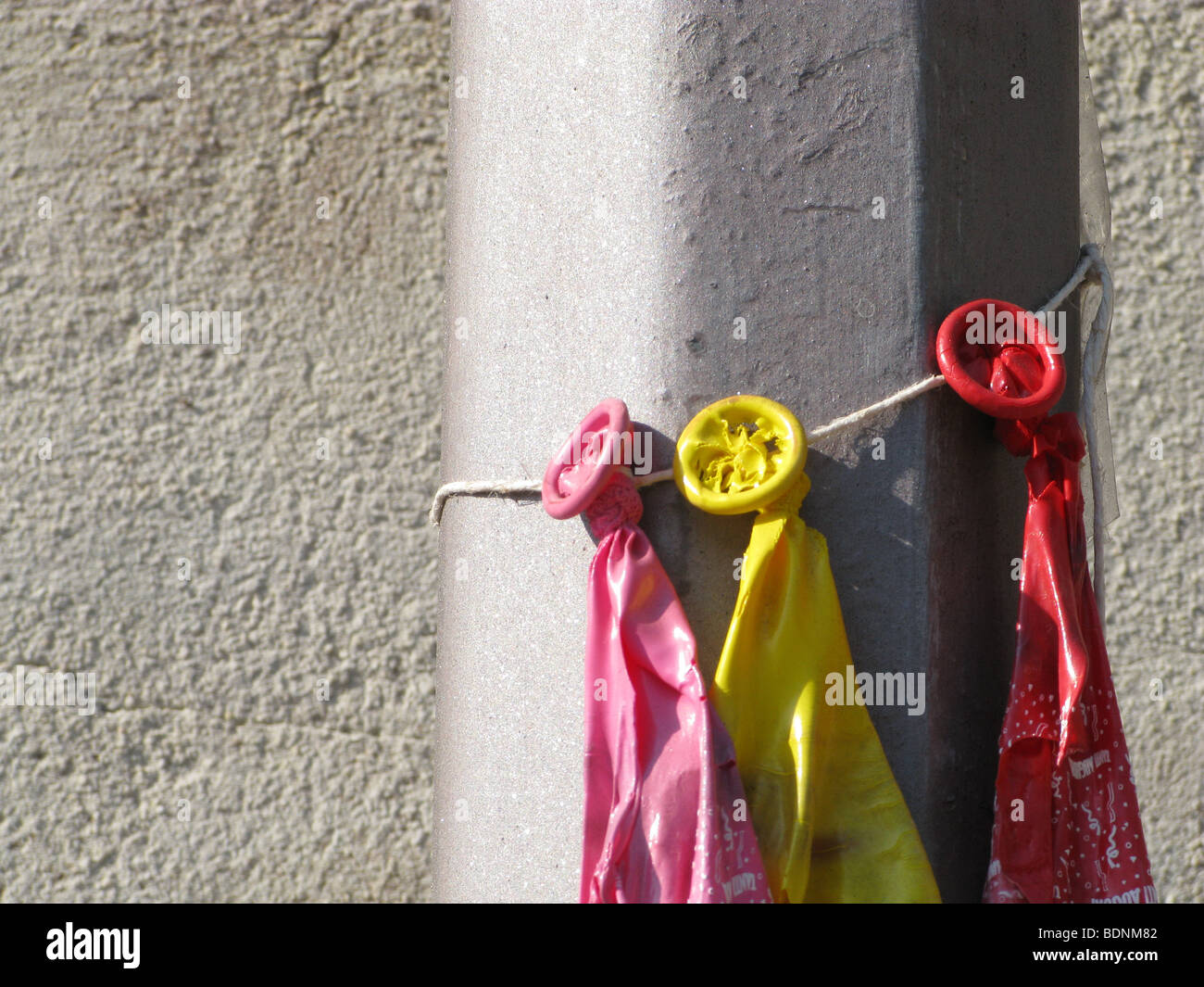 three burst balloons tied to lamp post outdoors in sun Stock Photo Alamy