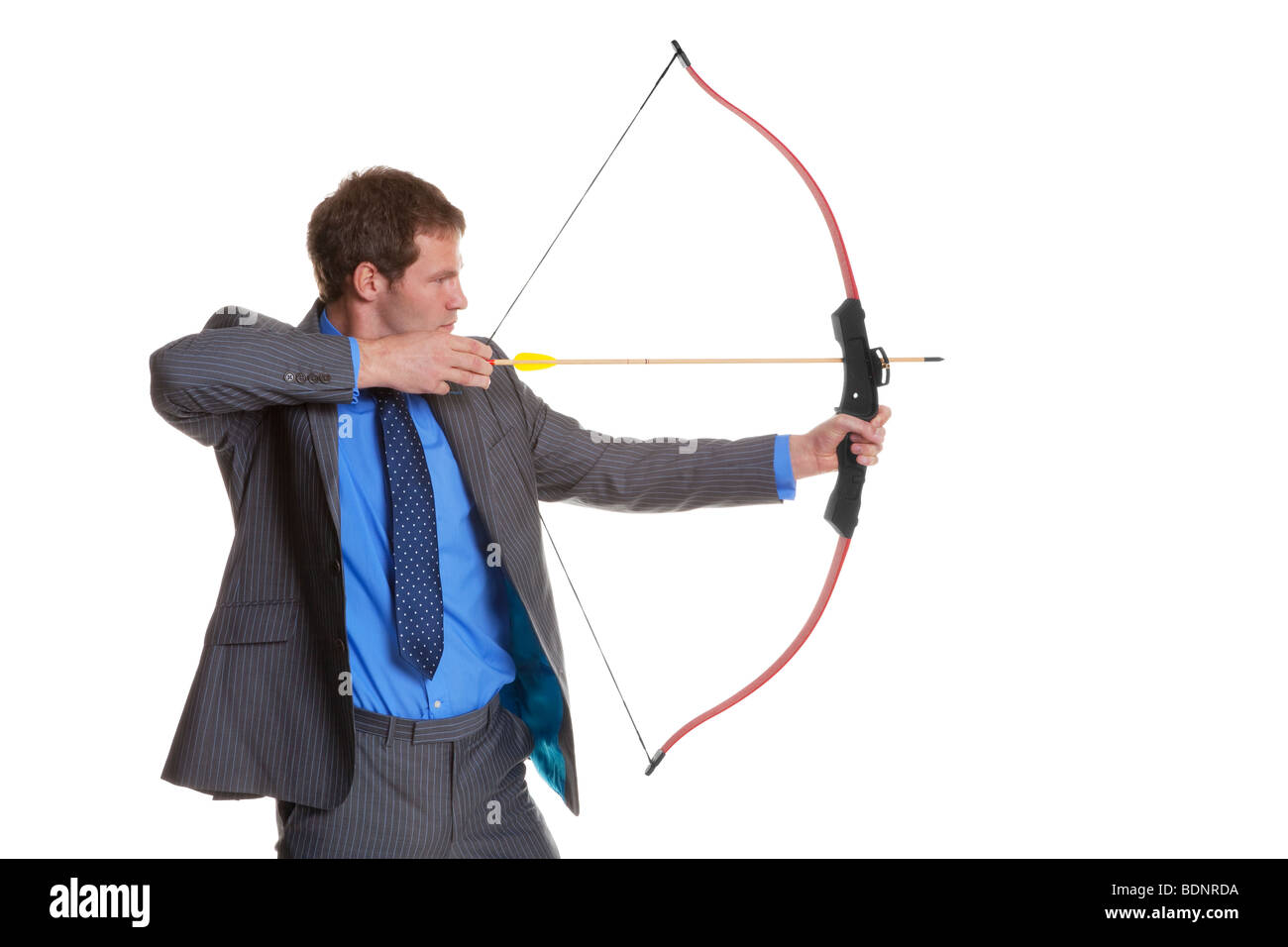 Businessman in pinstripe suit shooting a bow and arrow, isolated on a white background. Stock Photo