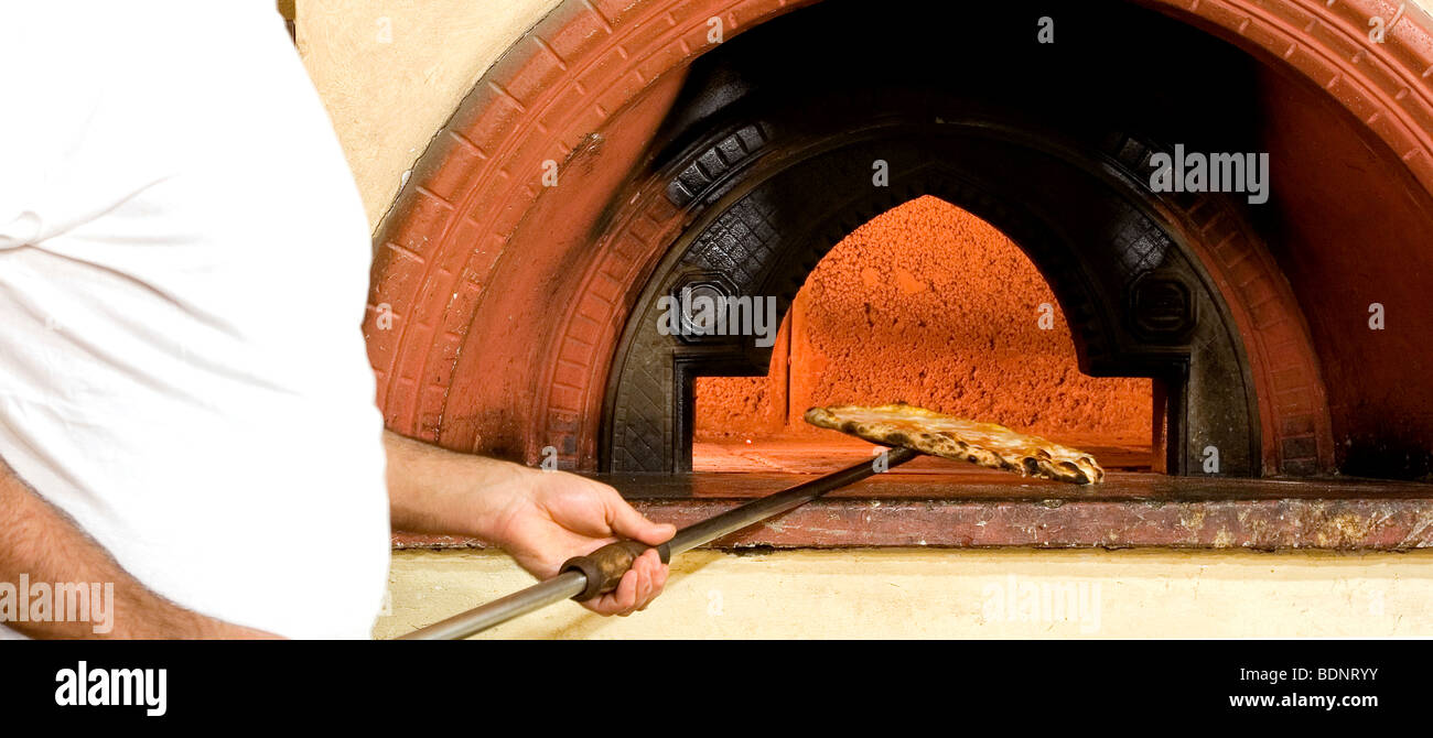 A chef removing a baked cheese pizza from the oven at the Hotel Astj pizzeria in Castrovillari, Cosenza, Calabria, Italy Stock Photo
