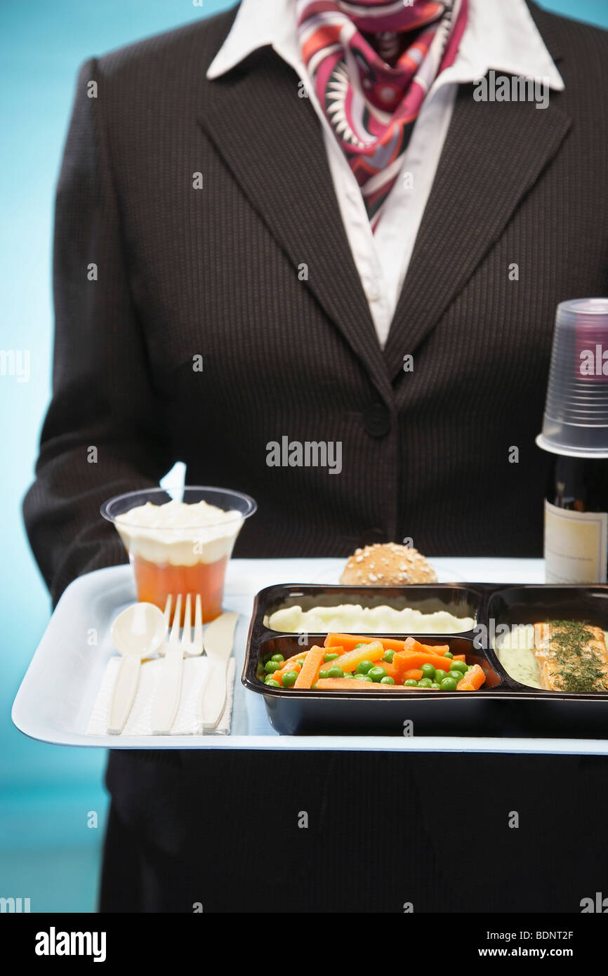 Stewardess holding tray with airplane food, mid section Stock Photo