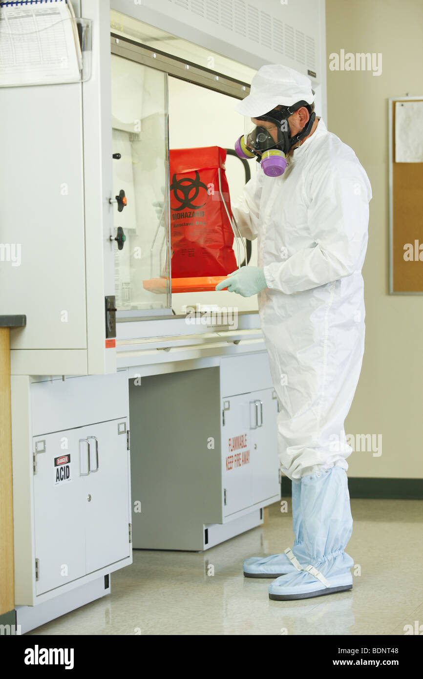 Scientist placing a biohazard bag into a fume hood Stock Photo