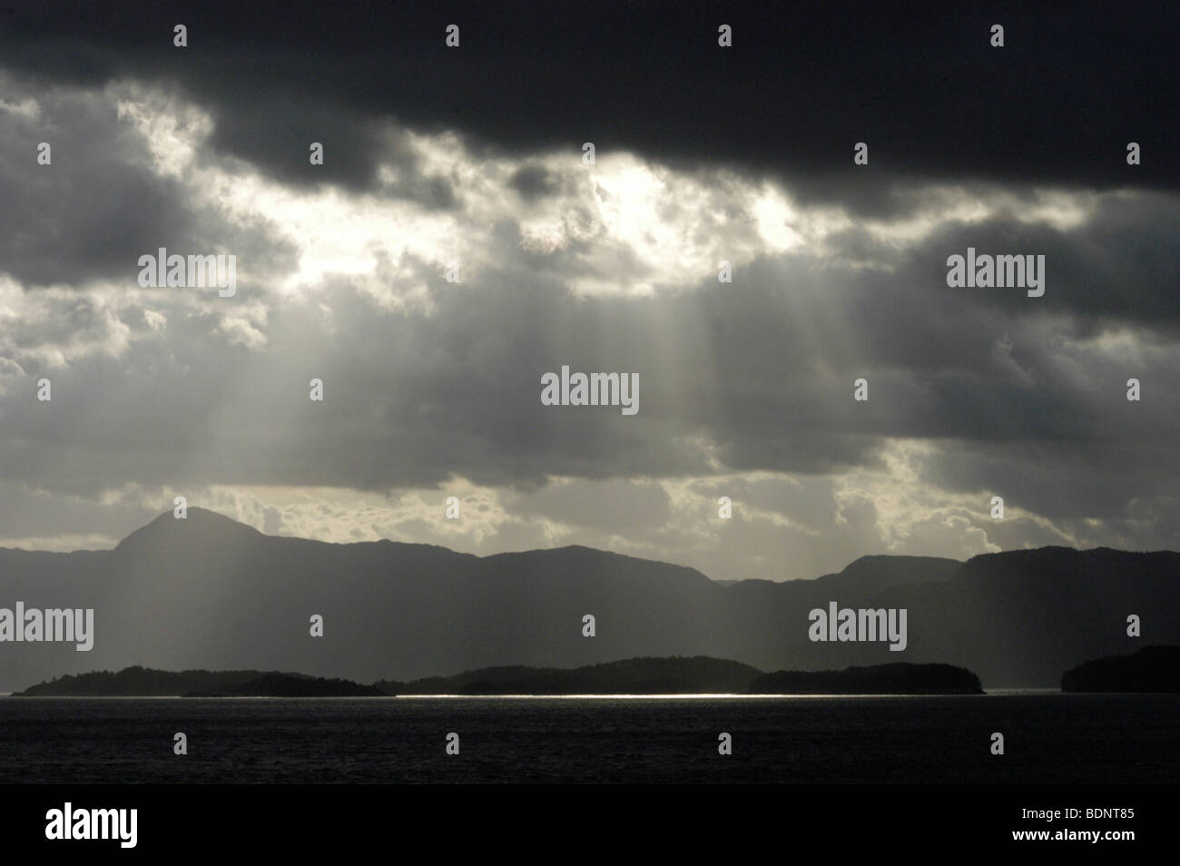 Sun breaks over Bjørnafjorden with the Folgefonn mountains on the horizon in Norway North Europe. Stock Photo