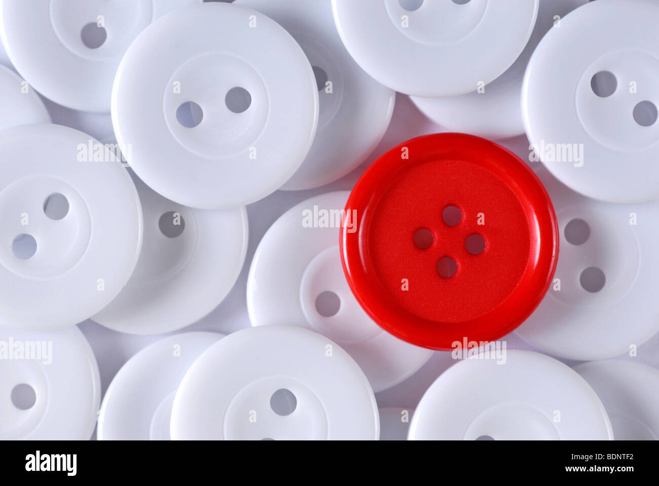 Red button under many white buttons, symbolic image for being different Stock Photo