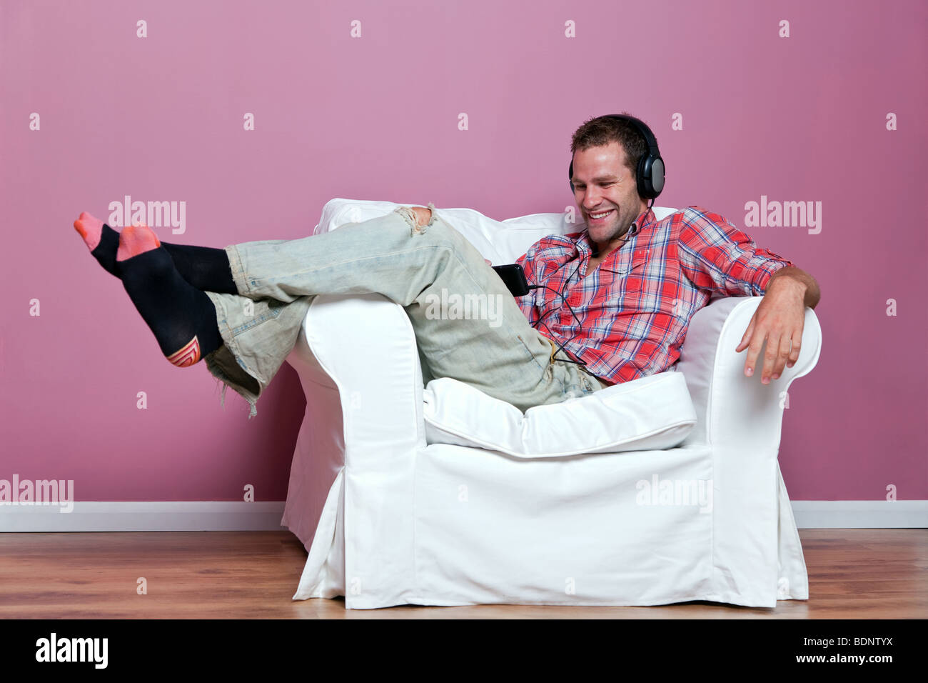 Relaxed male sitting listening to music on his mp3 player Stock Photo