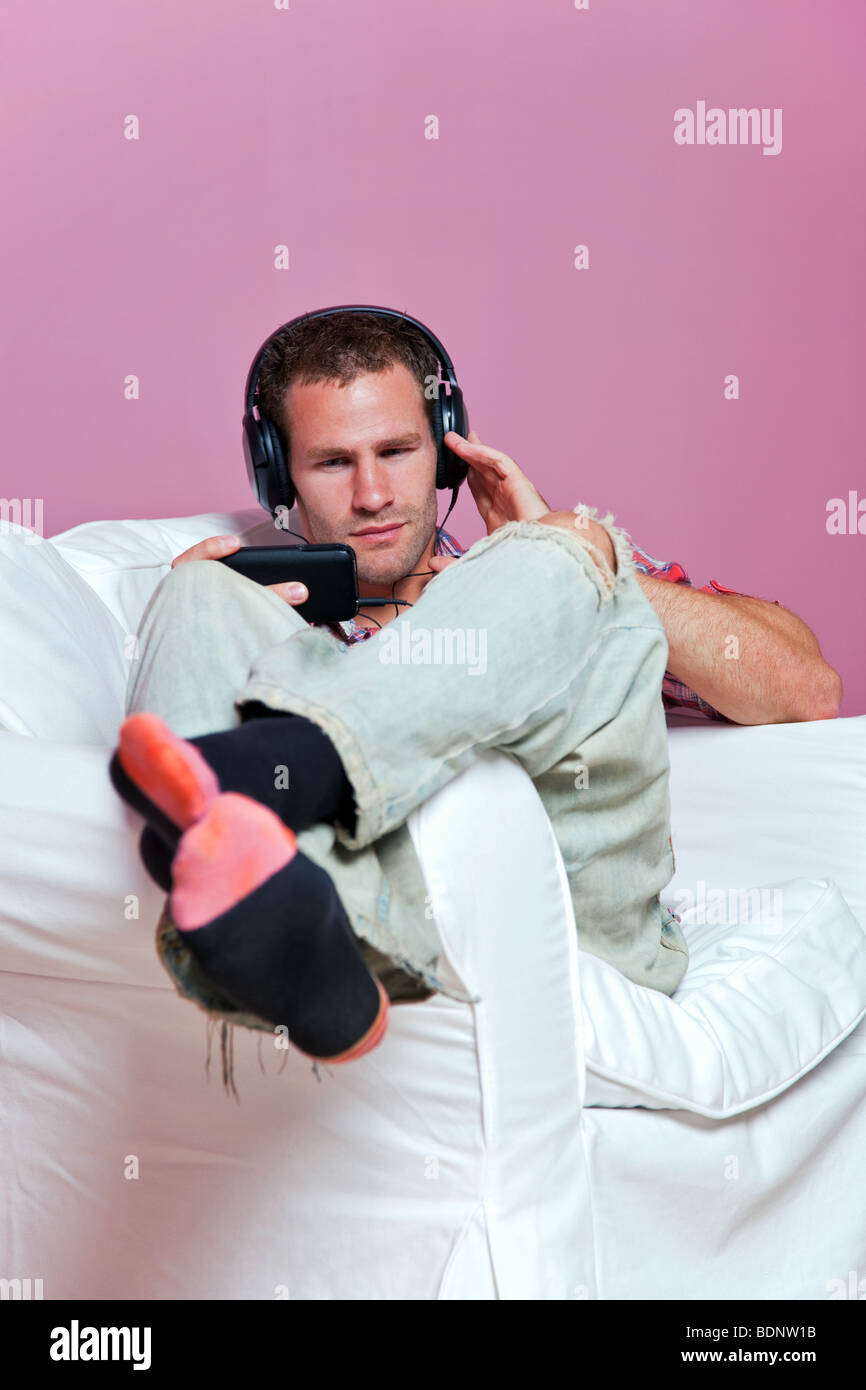 Relaxed male sitting listening to music on his mp3 player Stock Photo