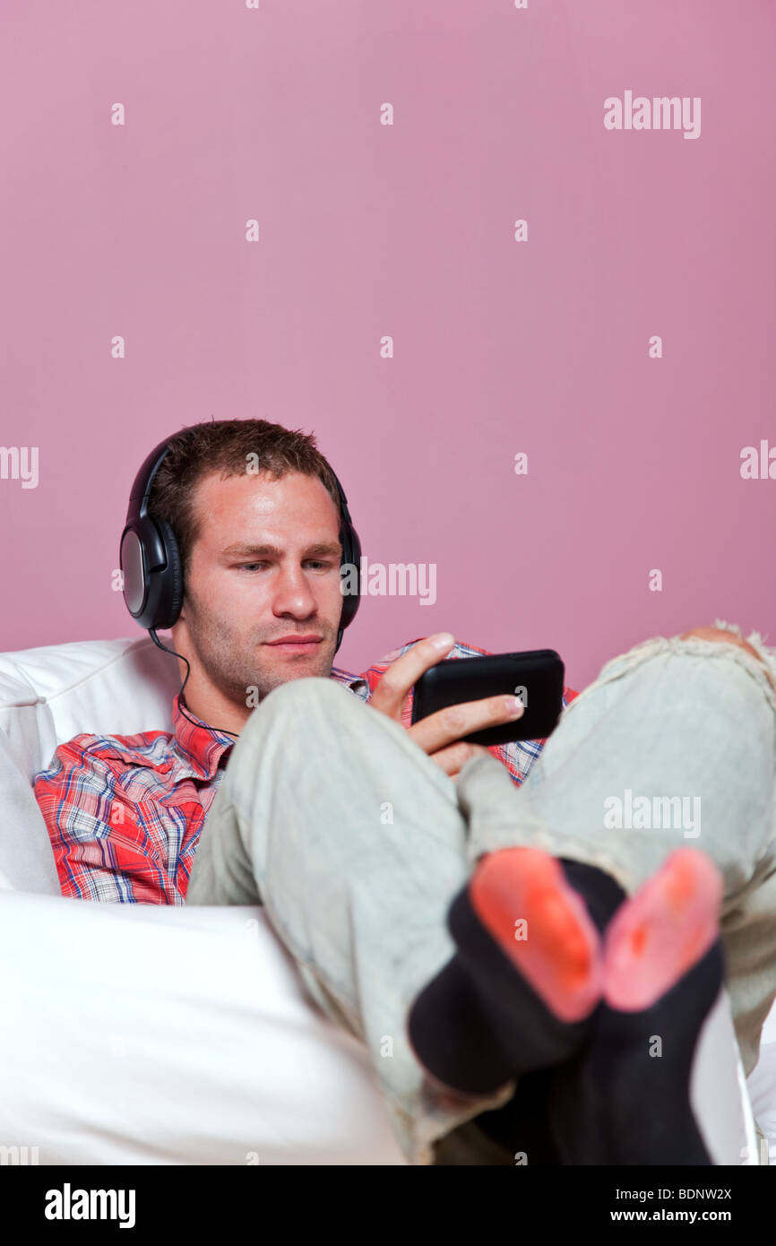 Relaxed male sitting listening to music on his mp3 player Stock Photo