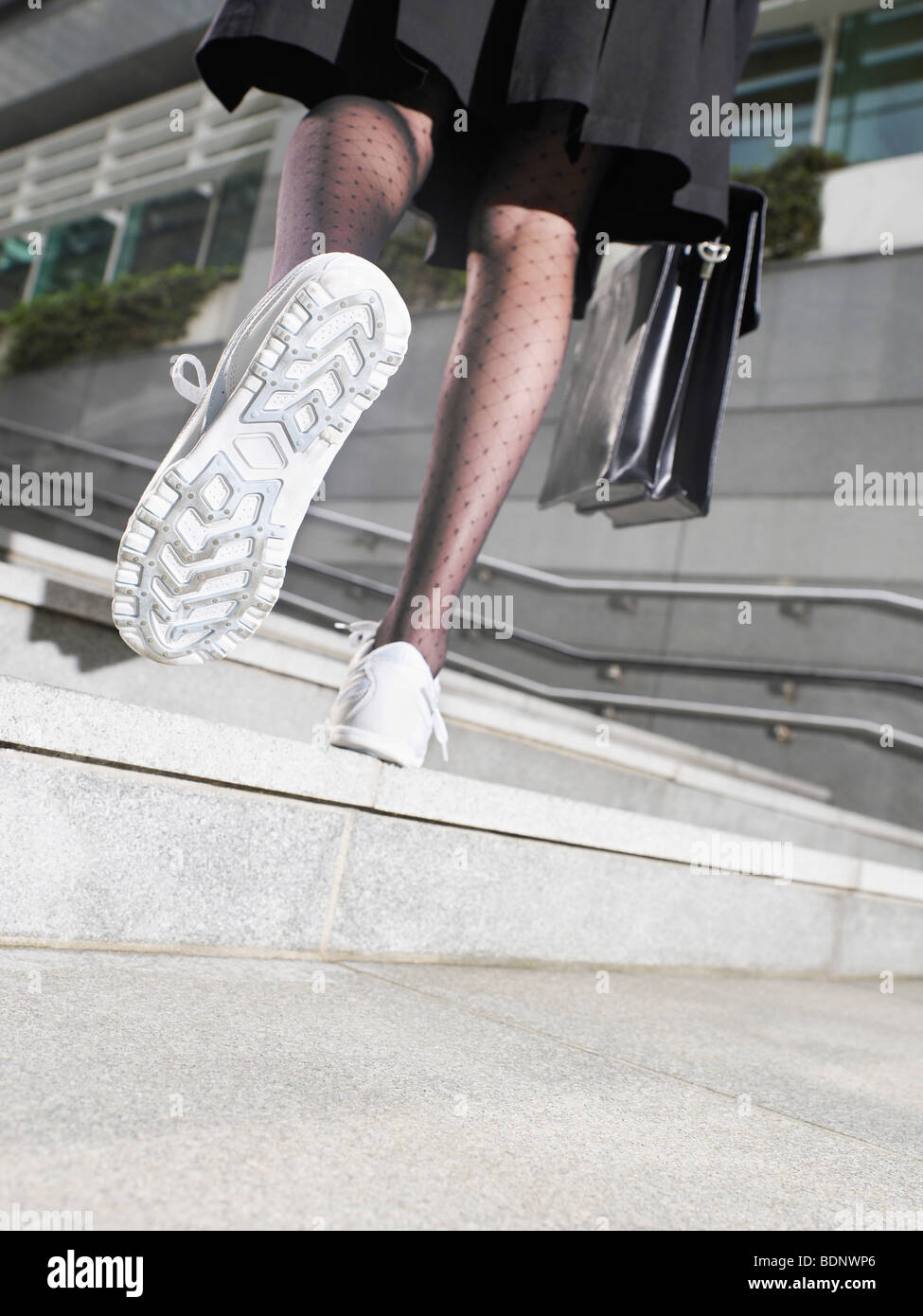 Business woman wearing running shoes, walking up steps, low section