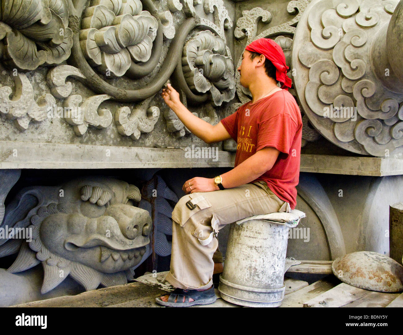 An Indian craftsman sculpting with damp concrete on the statue of Acharya Padmasambhav above