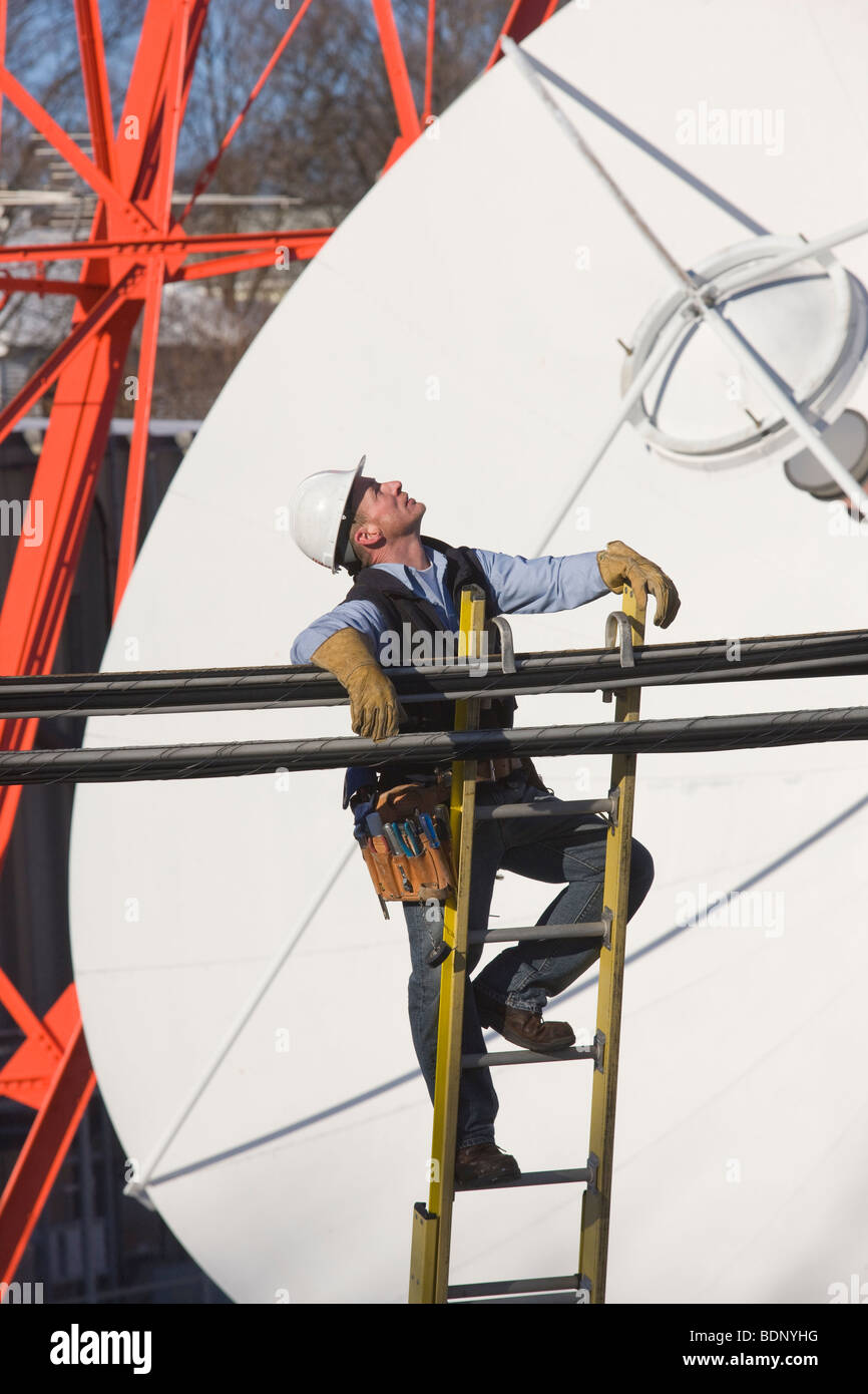 Cable lineman climbing a ladder to repair transmission line Stock Photo