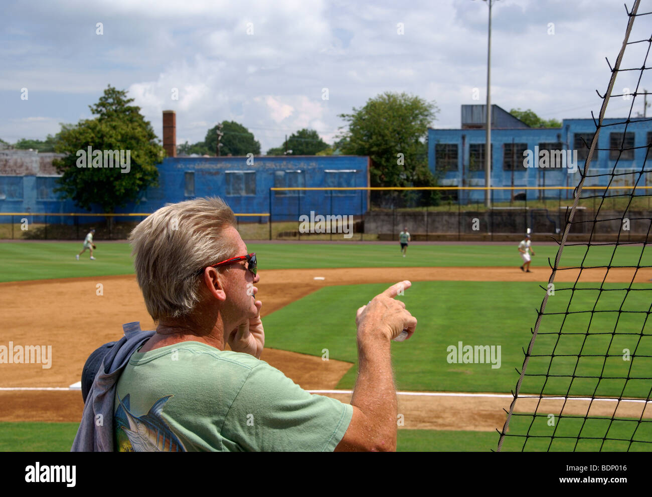 The old Durham baseball park in North Carolina, NC. Man pointing out in the athletic field while talking on the cell phone. Stock Photo