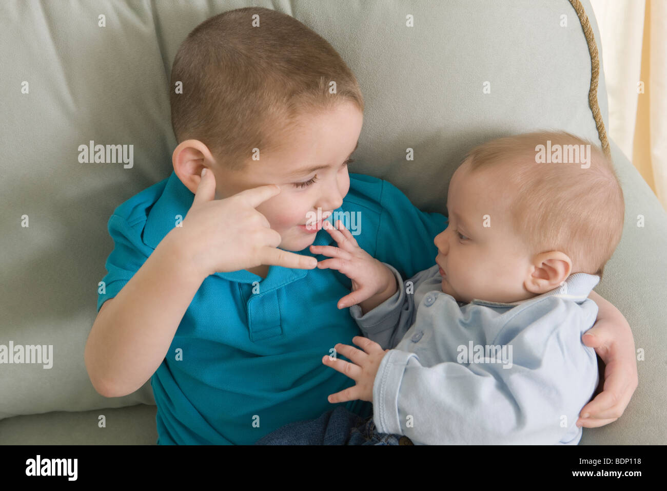 Boy signing the phrase 'I Love You ' in American Sign Language while communicating with his brother Stock Photo