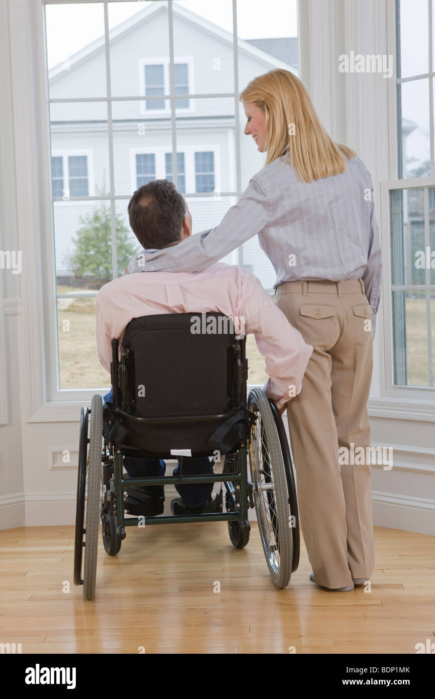 Man sitting in a wheelchair with a woman standing beside him Stock ...
