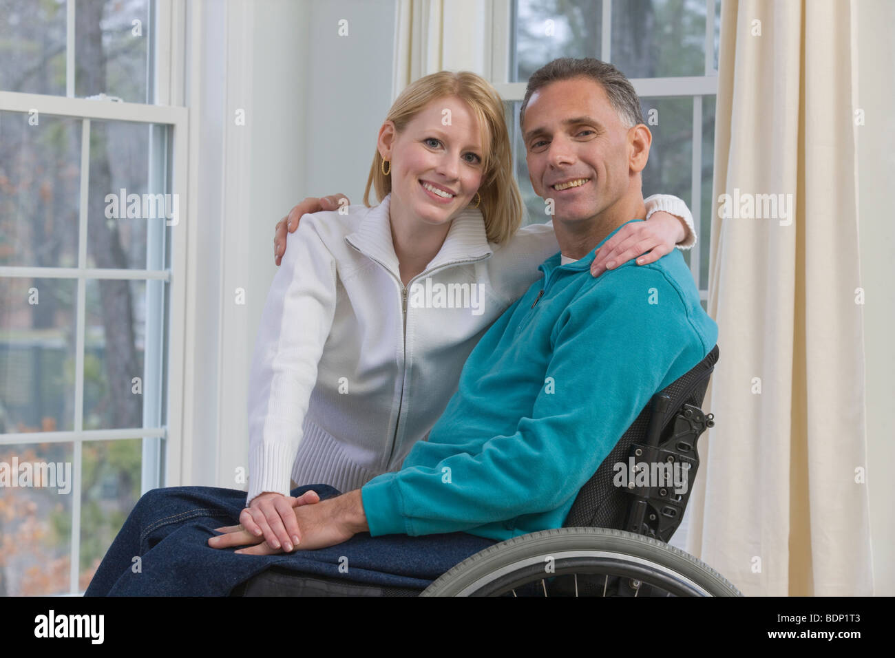 Man sitting in a wheelchair with a woman beside him Stock Photo - Alamy