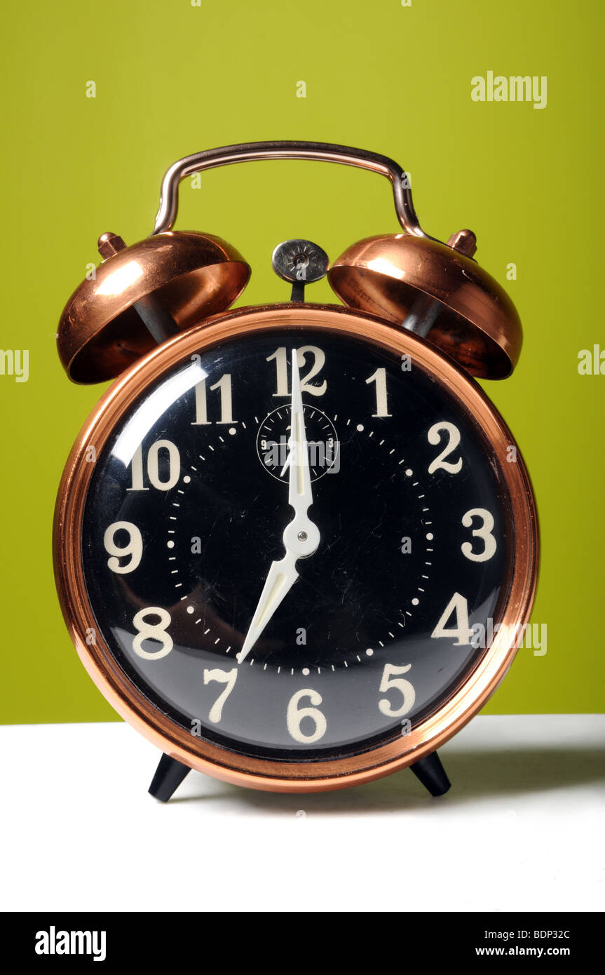 Vintage alarm clock on a white surface and green background Stock Photo