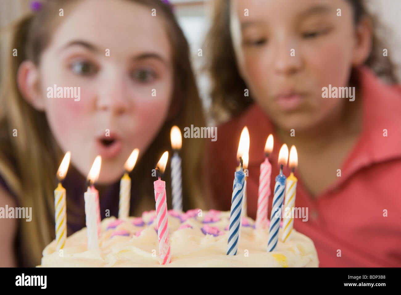 Two girls blowing out candles on a birthday cake Stock Photo Alamy