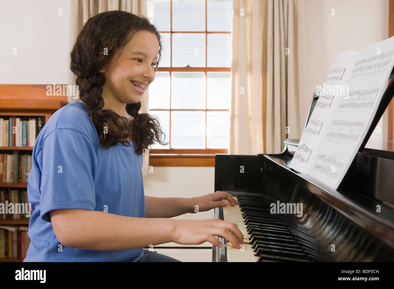 Girl reading a music sheet and playing a piano Stock Photo