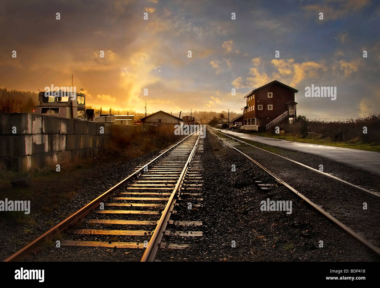 A railway track leading into the distance through a small station at sunset Stock Photo Alamy