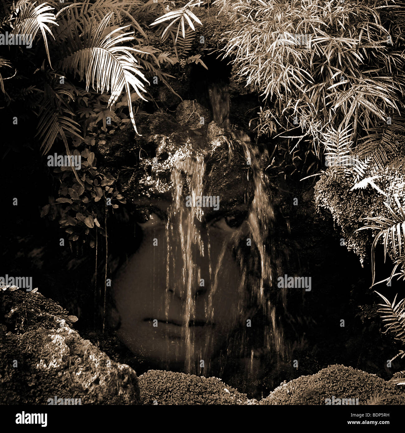 A water spirit gazes out from behind a small waterfall. Stock Photo