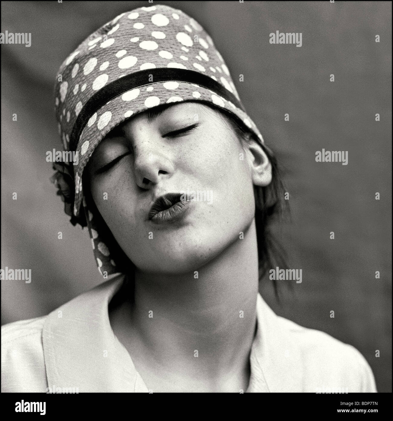 A young woman blowing a kiss wearing a hat with white spots Stock Photo